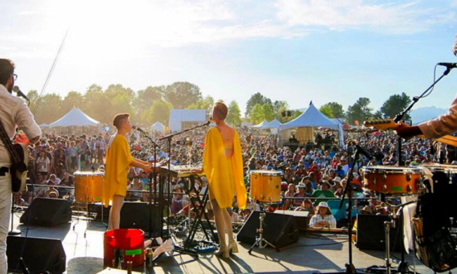 Lucius on mainstage of Vancouver folk Music Festival from the stage showing audience enjoying, tents and trees visible in the background.