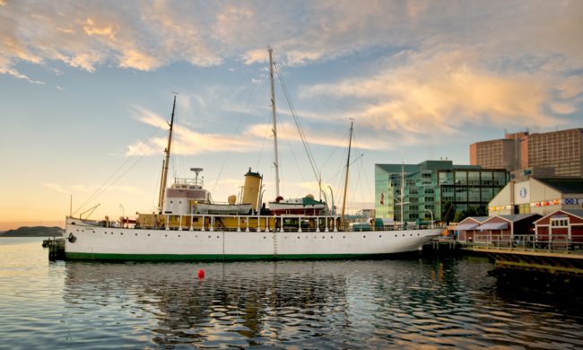 A large ship docked by a museum building at sunset.